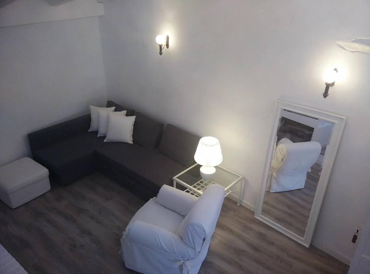 Salón con sofá en L, sillón blanco y espejo de pie