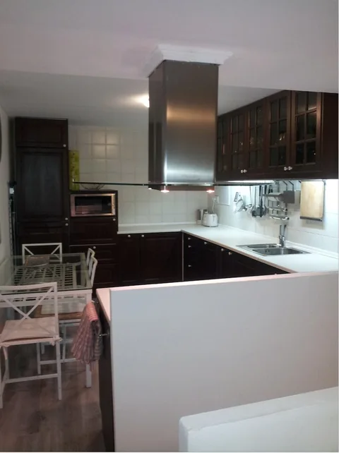 Cocina con muebles oscuros, encimera y campana extractora