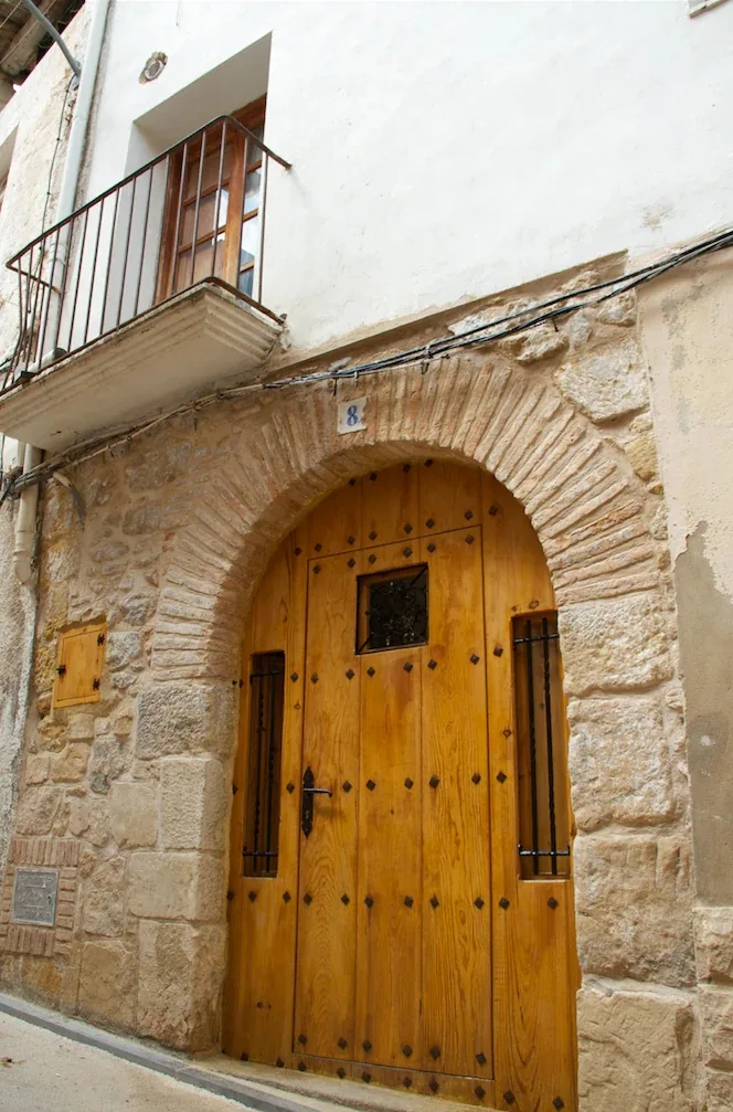 Fachada de piedra con puerta de madera y balcón