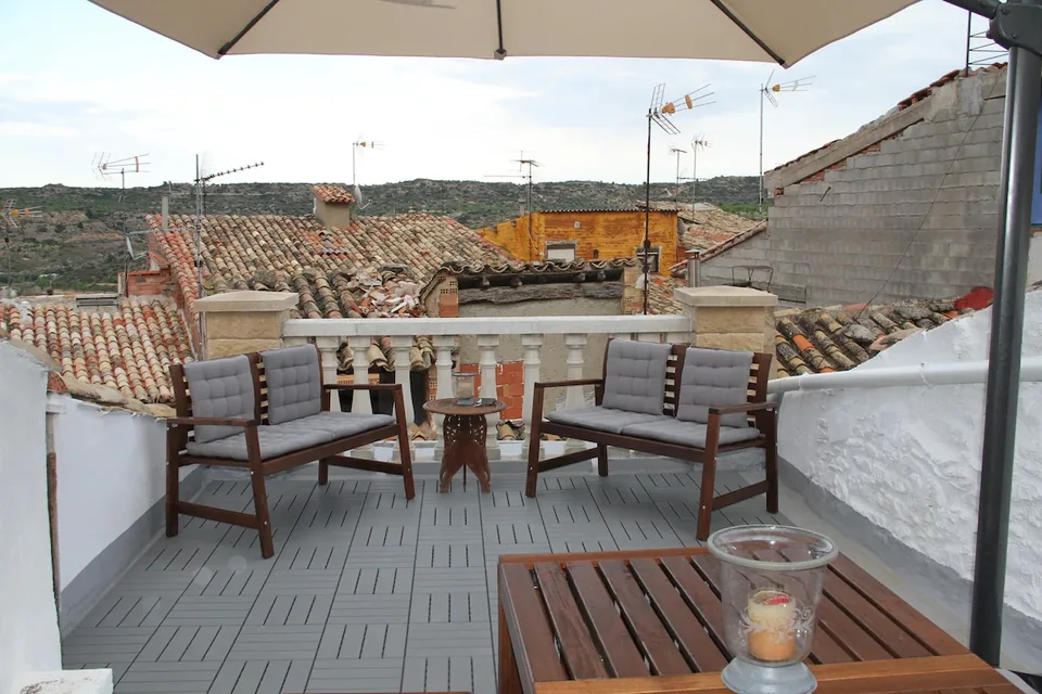 Terraza con asientos de madera, cojines y vistas a los tejados